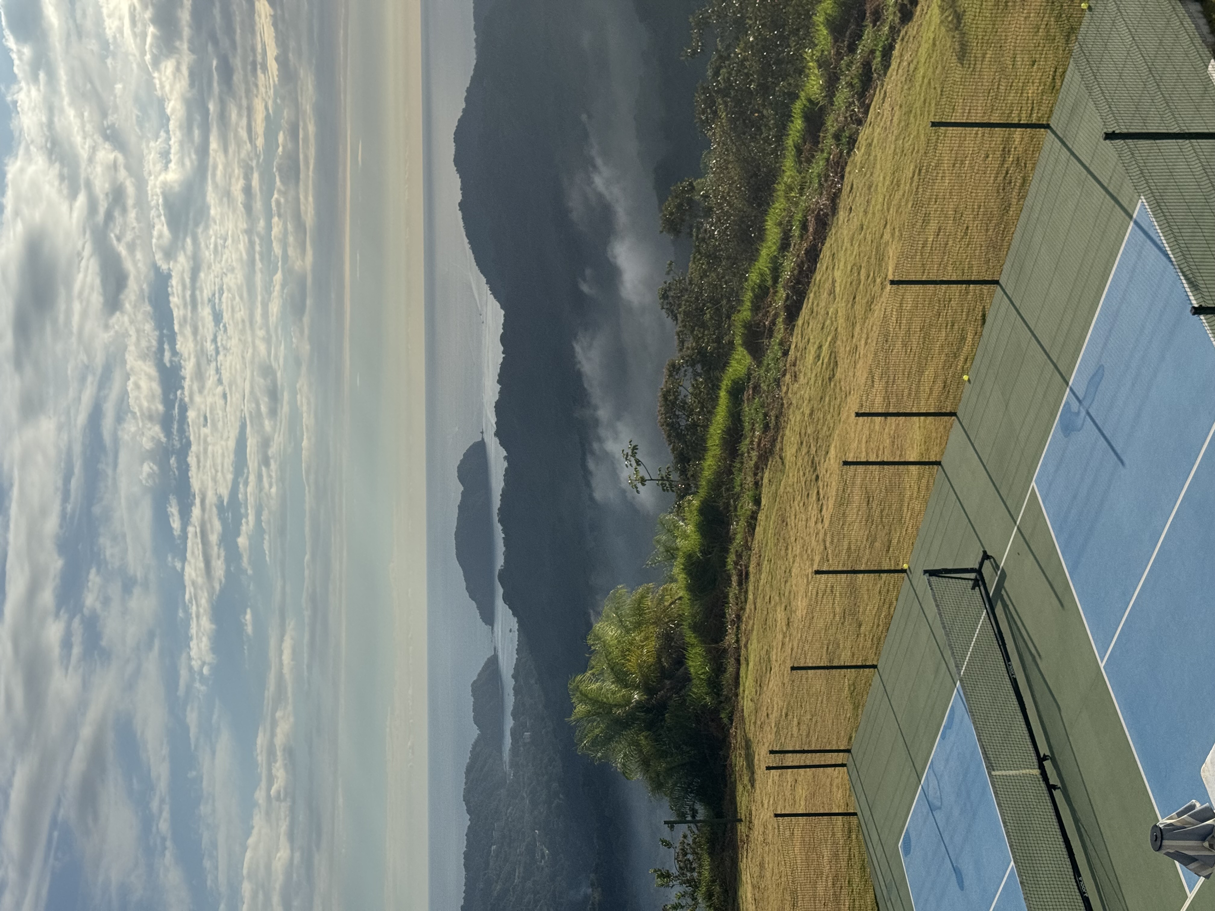 Pickleball court overlooking mountains and ocean with mist