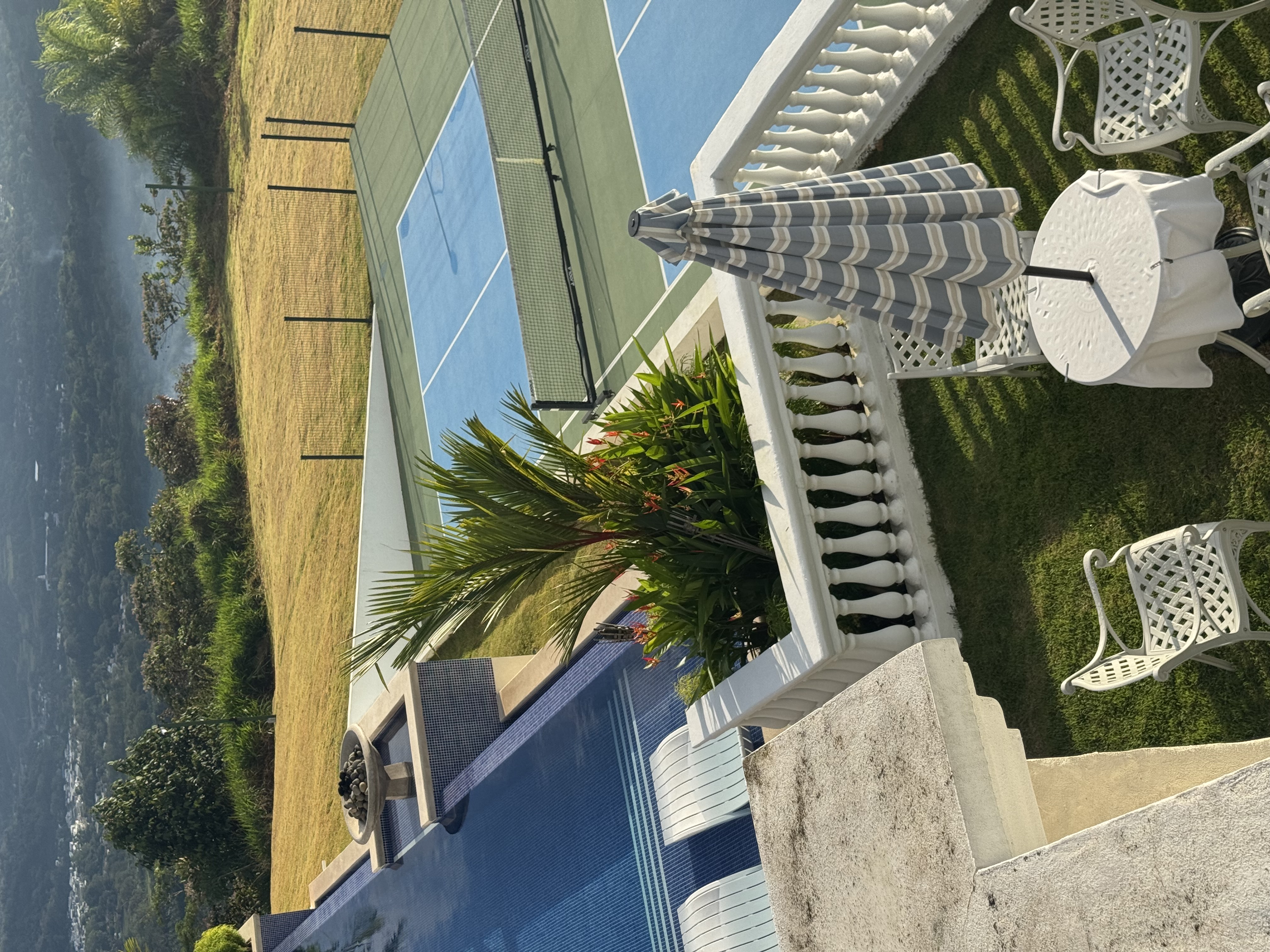 Pool and pickleball court overlooking ocean from above